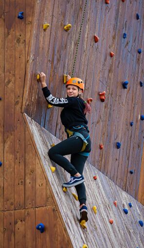 A camper climbs an outdoor climbing wall at Camp Maximum