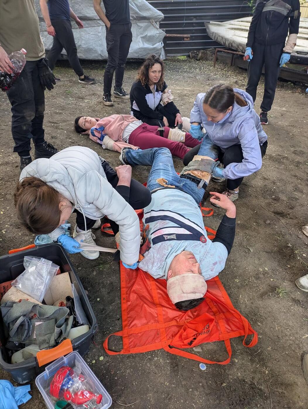 Students practice first aid on a training dummy during a class outdoors