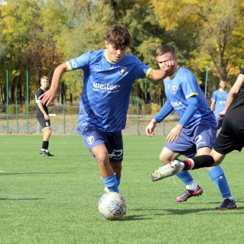 Young players in blue jerseys competing in a soccer match